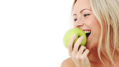 eine Frau isst einen grünen Apfel